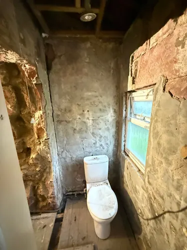 Small WC back to bare stone and floorboards around the window