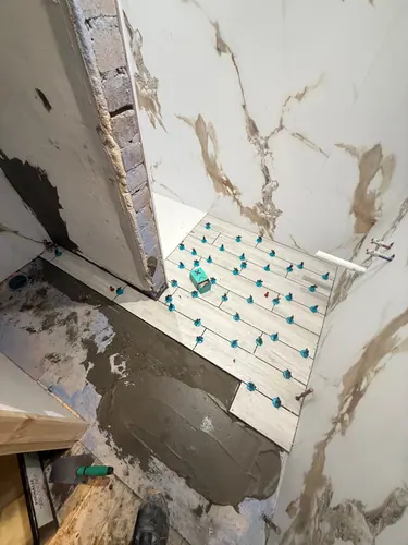 Wood-effect floor tiles being laid on levelling clips