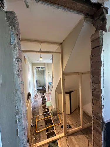 Hall floorboards lifted with cable reel and pipe runs through the joists