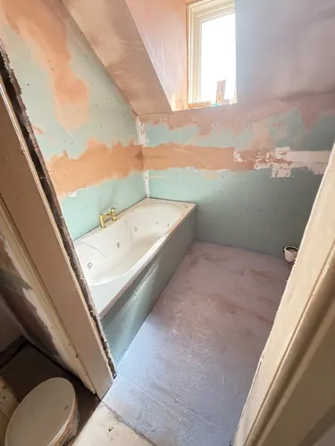 Boarded and plastered walls with the new bath set in place