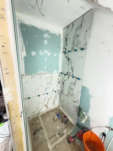 Marble-effect porcelain tiling started in the shower recess