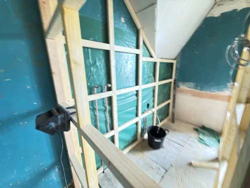 Inside the new stud walls with shower valve pipework and cabling in place