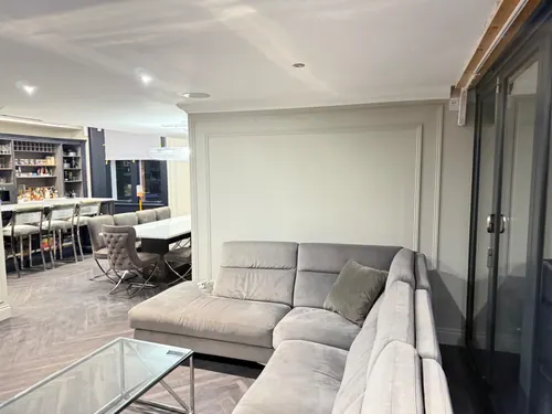 Living area sofa against the finished panelled wall looking through to the kitchen