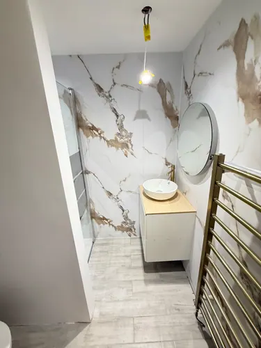 Finished shower room with countertop basin, mirror, towel rail and glass screen