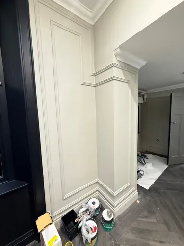 Painted corner return showing stepped mouldings and cornice with paint tins on the floor