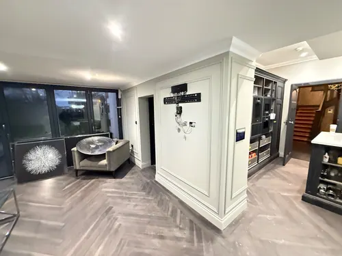 Open-plan space with painted panelling, television point and herringbone floor