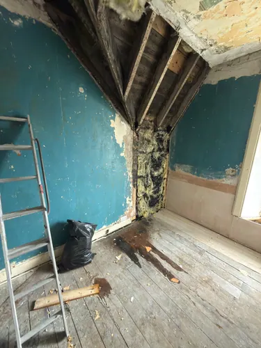 Corner of the bedroom stripped back showing old insulation and open joists