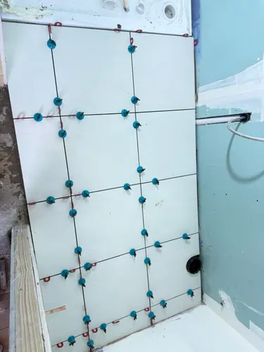 Wall tiles held with levelling clips above the new shower tray