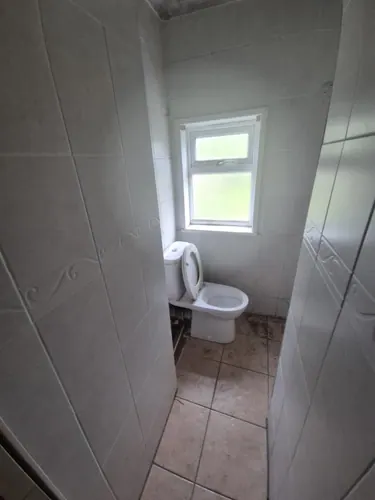 Separate WC lined in patterned white wall tiles with close-coupled toilet