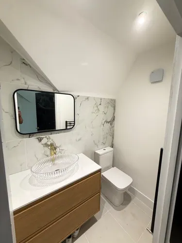 Finished en-suite showing WC, vanity unit, mirror and tiled floor