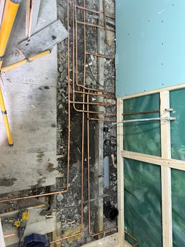 First fix copper pipework routed along the joists beside the boarded wall