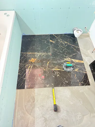 First black marble-effect floor tiles bedded beside the bath