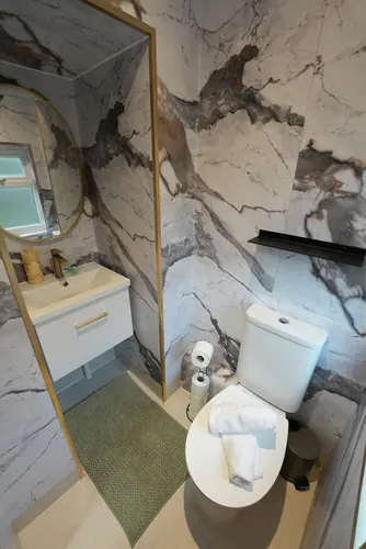 Round brass-framed mirror and wall-hung vanity unit in the finished WC