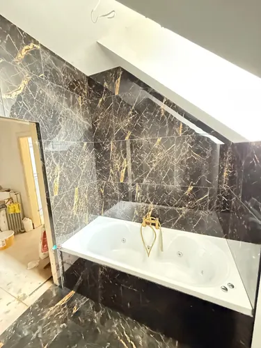 Tiling carried up the coombed ceiling above the bath with brass bath filler fitted