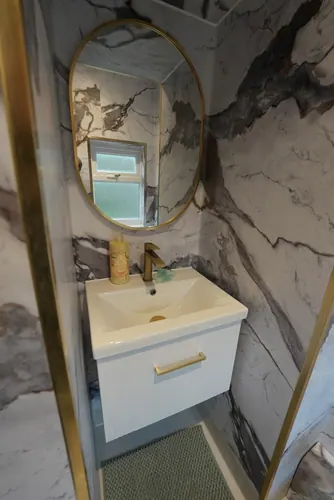 Wall-hung basin unit with brass tap and handle under the oval mirror
