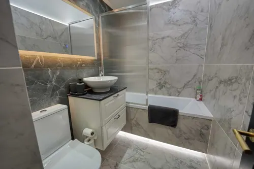 Finished bathroom showing wall-hung vanity, mirror cabinet and bath with reeded screen