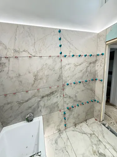 Large-format wall tiles set with levelling clips above the bath