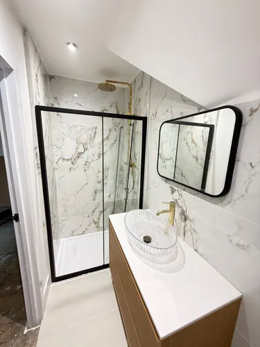 Completed en-suite with sliding shower enclosure, oak vanity unit and glass basin