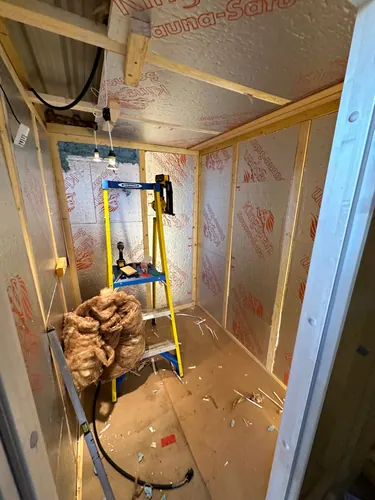 Timber studwork and foil-faced insulation with temporary lighting and cable dropped in