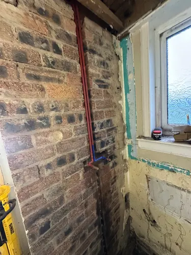 Copper hot and cold feeds run on the exposed brick wall