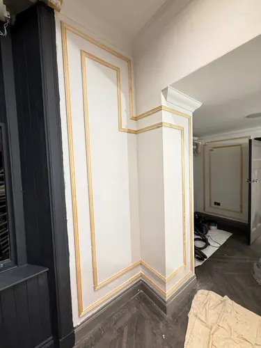 Bare timber panel mouldings fitted around a corner return and cornice
