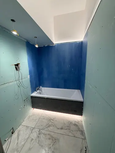 Boarded walls with blue tanking behind the bath and tiled floor complete