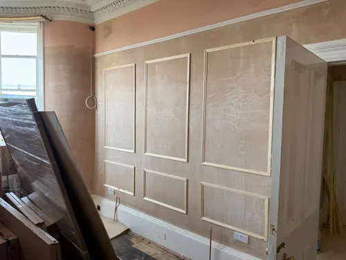 Panel mouldings pinned to the plaster wall beside the bay window
