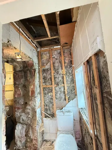 Stone wall and ceiling joists exposed after tiles and plaster came off