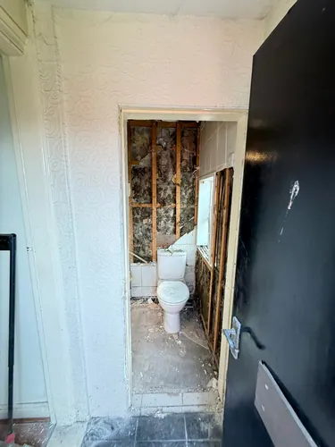View through the doorway into the WC with wall tiles and plaster removed