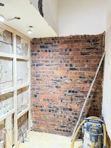 Bare brick wall exposed with new timber studwork and cabling to one side