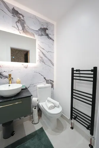 Countertop basin, brass tap and ladder radiator against plain white walls