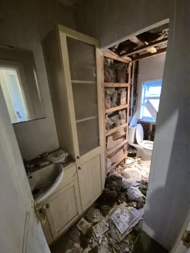 Basin and built-in cupboard still in place as the adjoining wall is opened up