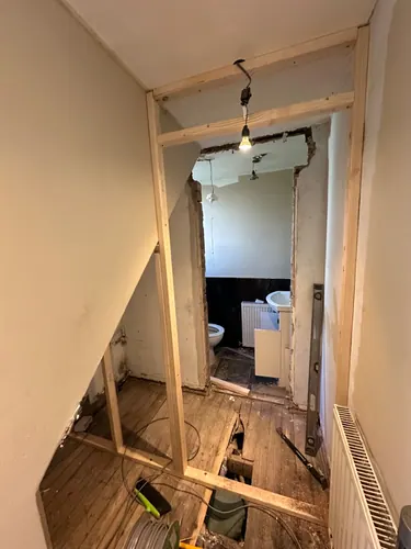 New timber door opening framed in the hall with old suite visible beyond