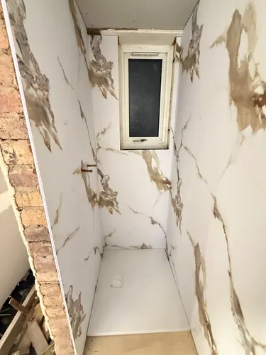 Low-profile shower tray fitted between the panelled walls