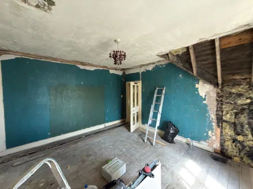 Teal painted bedroom walls with skirtings removed and floorboards lifted