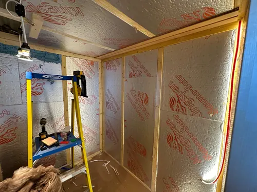 Insulated walls and ceiling with red cable run down the corner stud