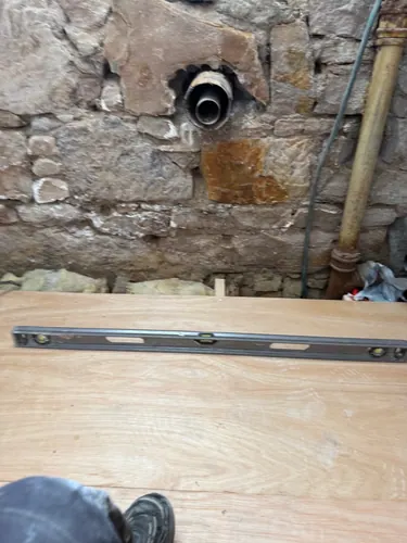 Spirit level on the new ply floor deck beside the stone wall and waste outlet