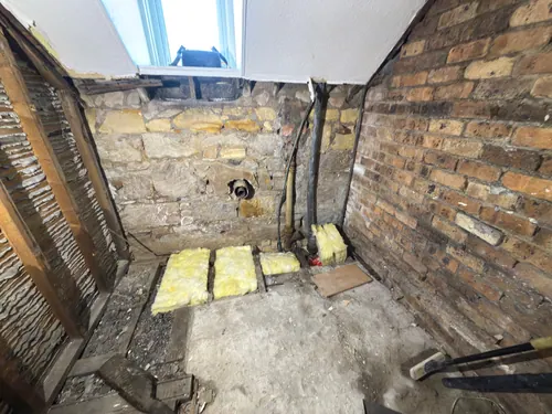 Floor taken back to joists with insulation laid and waste pipe through the stone wall