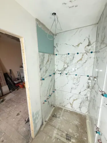 Tiled shower area with ceiling outlet cable and levelling clips still fitted