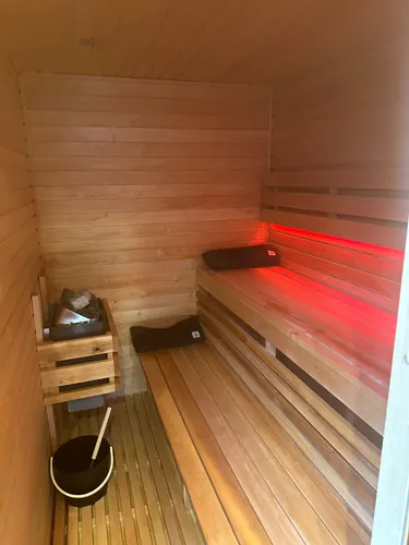 Completed sauna with slatted floor, bucket and ladle, headrests and red bench lighting