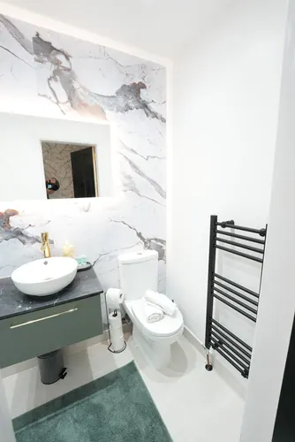 Finished shower room with backlit mirror, dark vanity and black towel radiator