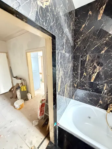 Tiled bath surround with the landing visible through the open door