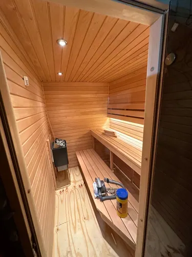 Timber-lined sauna with ceiling downlights and glass door hung