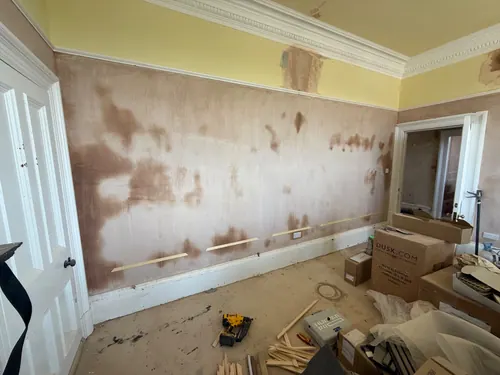 Timber setting-out battens tacked to a stripped wall in the second room