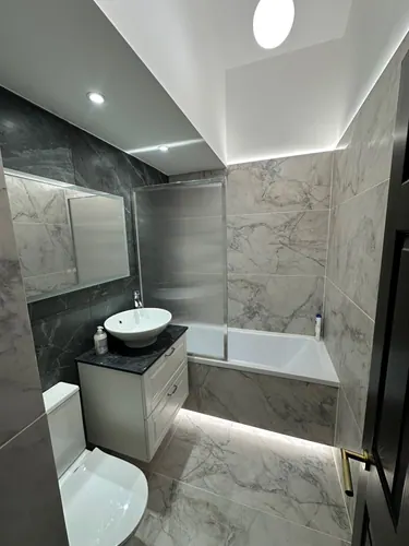 Completed bathroom with vanity basin, bath screen and recessed lighting