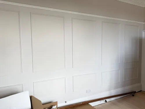 White painted panelling running the length of the wall above new flooring